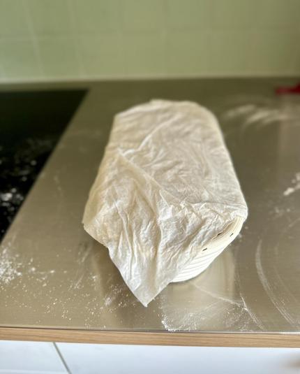Das Gärkörbchen von der Stirnseite, es ist mit einem feuchten Stück Küchenpapier abgedeckt.