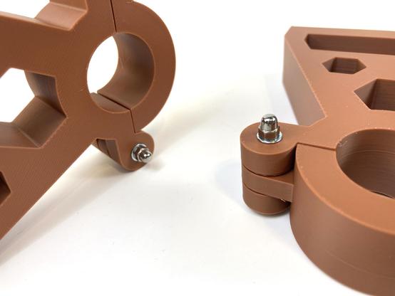 Two 3D printed clamping brackets with lock nuts on bolts that fit just right.