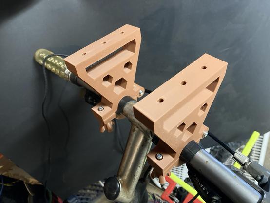 A bike handlebar with two 3D printed mounts attached.
