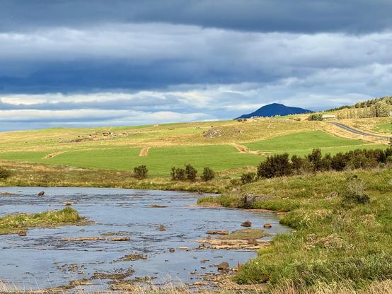 The Icelandic countryside with dramatic clouds and a mountain and river