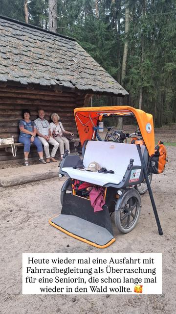 Instastorybild. Drei Leute auf einer Bank an einer Hütte und die Rikscha. Text: „Heute wieder mal eine Ausfahrt mit Fahrradbegleitung als Überraschung für eine Seniorin, die schon lange mal wieder in den Wald wollte.“