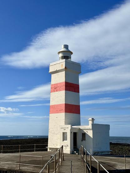 The old Garðskagi lighthouse operated from 1897 until 1944. It has a square shape and distinctive orange-red bands around it. 
