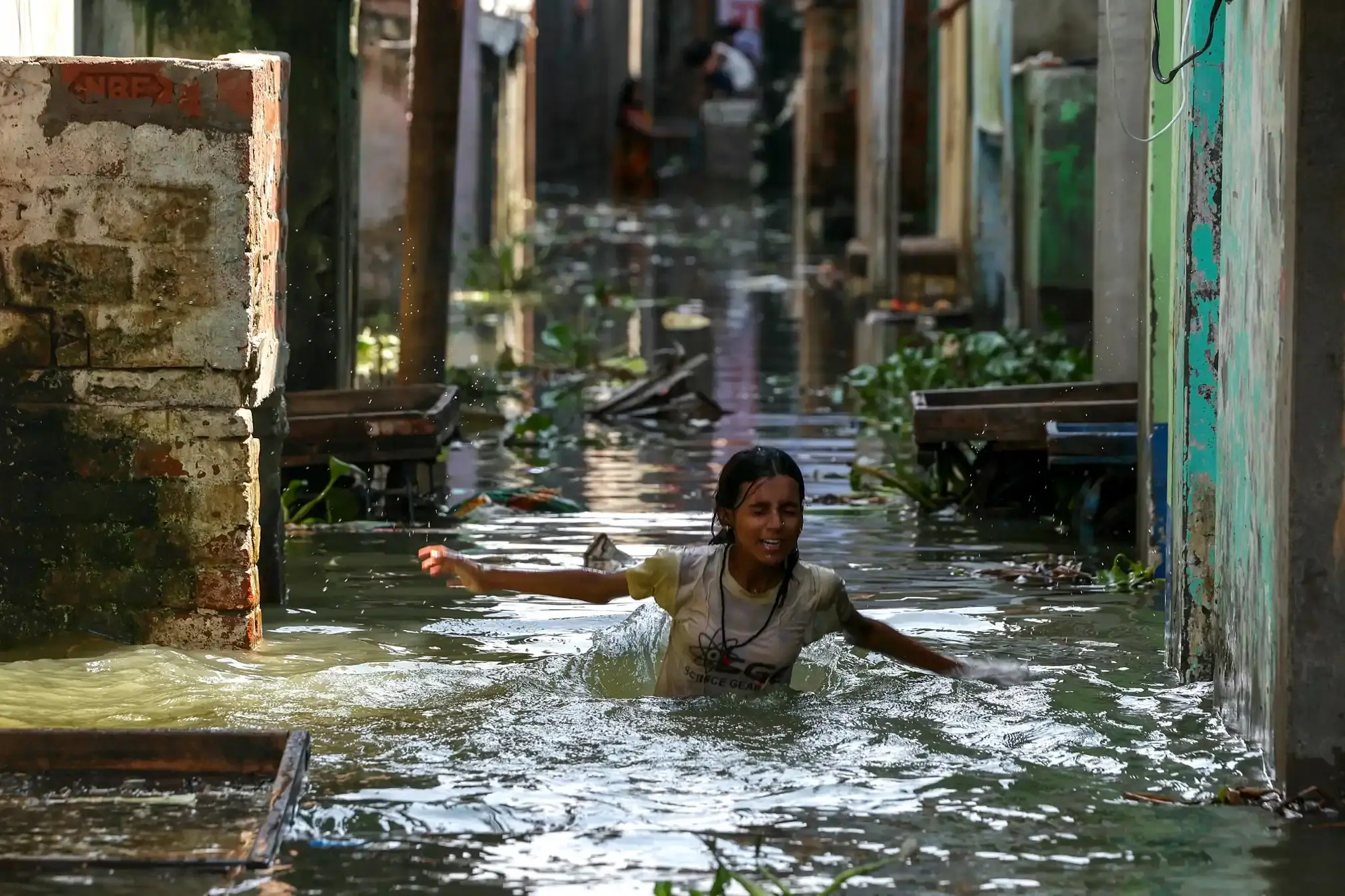 A girl wades through a flooded residential area after the water level of the Varuna River rose again.
