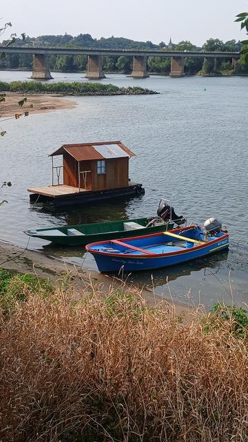 Trois petits navires individuels sur la Loire, un pont routier dans l'arrière plan, par beau temps