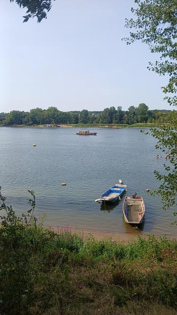Deux petits navires individuels sur la Loire, un navire touristique en bois dans l'arrière plan, par beau temps