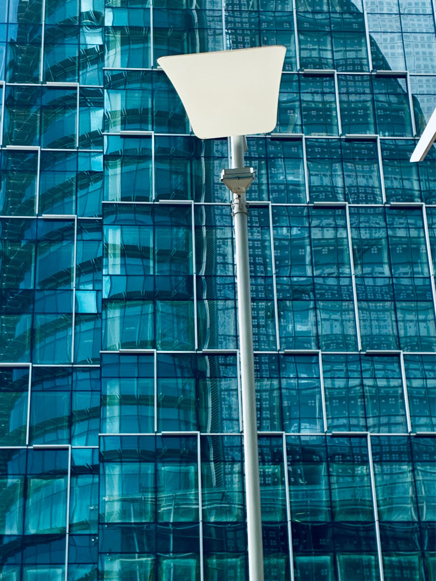 Fachada de metal y cristal con una farola delante.