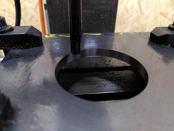160x160mm steel plate with a 68.2mm hole cut in it. The black clamps to hold it to the table are visible and so is the cutting tool