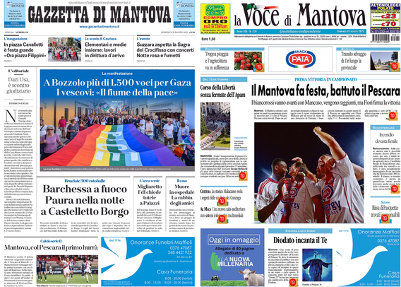 Un giornale illuminato su uno sfondo nero, con due testate principali affiancate. A sinistra c’è il titolo "Gazzetta di Mantova" e a destra "la voce di Mantova".   Sulla sinistra, un articolo con una fotografia di una grande bandiera arcobaleno portata da molte persone, con il titolo "A Bozzolo più di 1.500 voci per Gaza I vescovi: «Il fiume della pace»".  Al centro e sulla destra, una foto di un gruppo di uomini con maglie da gioco (sembra una squadra sportiva), con il titolo "Il Mantova fa festa, battuto il Pescara".  Sono presenti anche altri articoli e spazi pubblicitari con testi più piccoli.