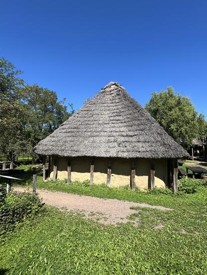 Ein mit Schilf gedecktes Haus mit einer Lehmmauer (Rekonstruktion eines Wohnstallhauses).