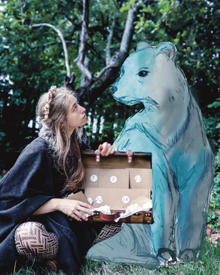 Femme assise tenant dans ses main une valise avec des enveloppes numérotées. Derrière elle, un ours dessiné à l'aquarelle la regarde sereinement.
