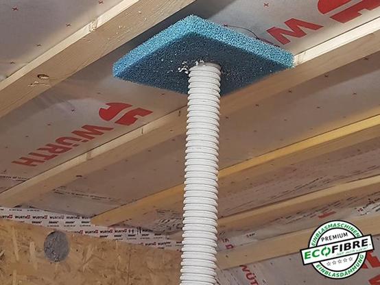 Ein Einblasschlauch steckt in einer Dampfbremse einer Innendecke. Ein Abdichtschwamm dient am Schlauch zur Staubreduzierung. 