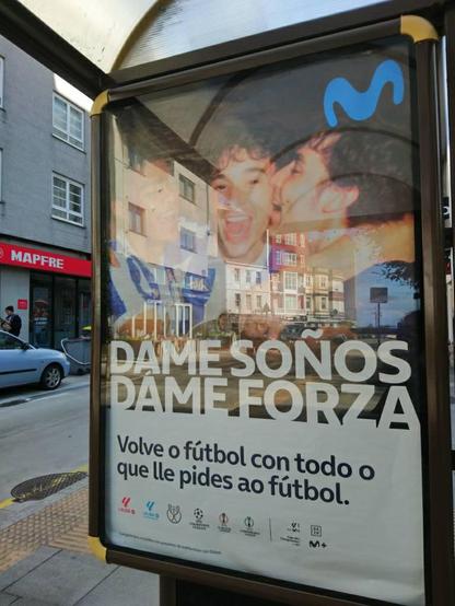 Cartel publicitario de la liga de fútbol (España) y Movistar, con aficionados de fútbol en camiseta celebrando algo y con el texto en gallego "Dame soños, dame forza. Volve ó fútbol con todo o que lle pides ao fútbol" (Dame sueños, dame fuerza. Vuelve el fútbol con todo lo que le pides al fútbol)