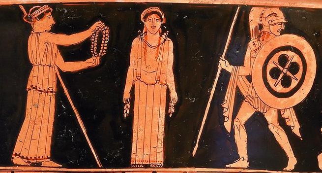 Detail of a red-figure vase painting. The gods bestow their gifts upon the first woman Pandora. She is depicted as a forward-facing, statuesque figure. The goddess Aphrodite steps forward to crown her with a wreath of myrtle. Ares, armed with a shield and spear, stands on Pandora's other side.