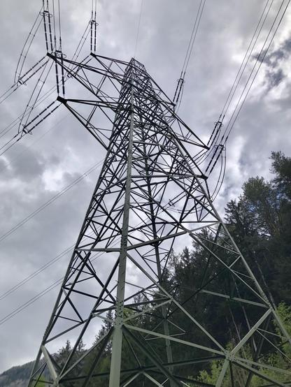 Ein Hochspannungsmast aus der Nähe von seitlich unten fotografiert.