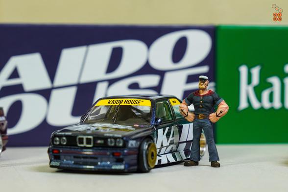 A BMW M3 E30, Kaido Works V1 by Mini GT in 1:64 scale with 1:64 figure on AREA 164