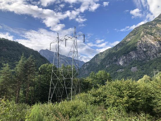 Ein Strommast in einem Bergtal.