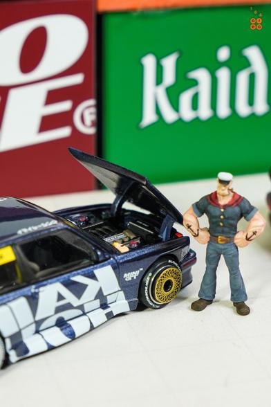 A BMW M3 E30, Kaido Works V1 by Mini GT in 1:64 scale with 1:64 figure on AREA 164