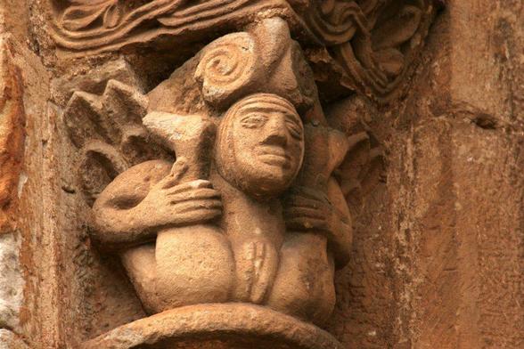 Sculpture of a female figure grabbing her thighs and pulling them up to expose her vulva.