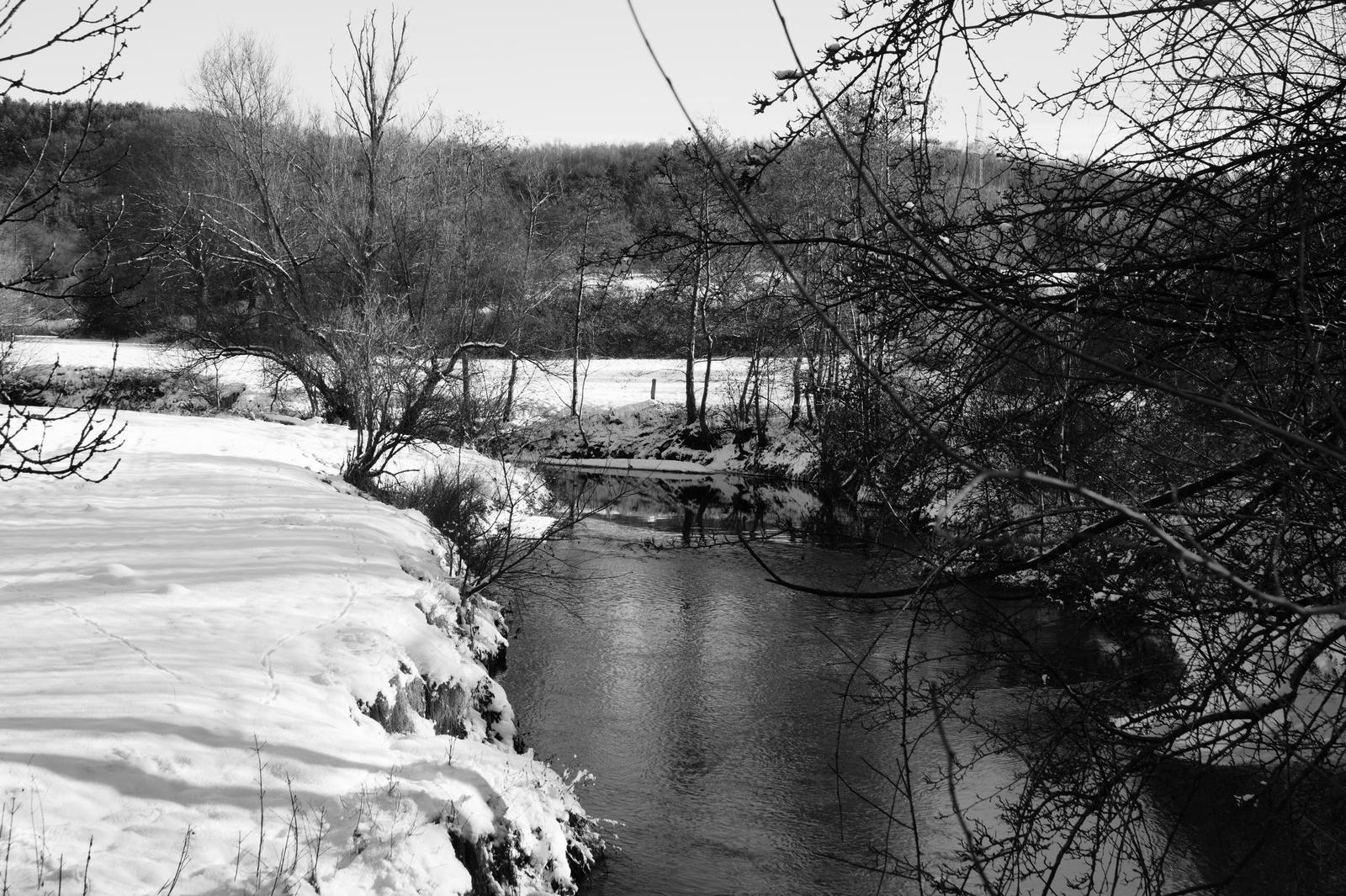 Das Bild zeigt den Fluss Wurm bei Herzogenrath im Winter. Der Fluss ist in der Mitte vom Bild, das Ufer auf der linken Seite ist eine steile Böschung, an die sich eine schneebedeckte Wiese anschliesst. Rechts im Bild ragen die Äste eines Baum ins Bild. Im Hintergrund macht der Fluss eine Kurve nach links, dahinter ist noch eine schneebedeckte Wiese zu erkennen. Noch weiter im Hintergrund steigt die Landschaft zu einem Hügel an, der von Wald bedeckt ist. Das Bild zeigt den Fluss Wurm bei Herzogenrath im Winter. Der Fluss ist in der Mitte vom Bild, das Ufer auf der linken Seite ist eine steile Böschung, an die sich eine schneebedeckte Wiese anschliesst. Rechts im Bild ragen die Äste eines Baum ins Bild. Im Hintergrund macht der Fluss eine Kurve nach links, dahinter ist noch eine schneebedeckte Wiese zu erkennen. Noch weiter im Hintergrund steigt die Landschaft zu einem Hügel an, der von Wald bedeckt ist.