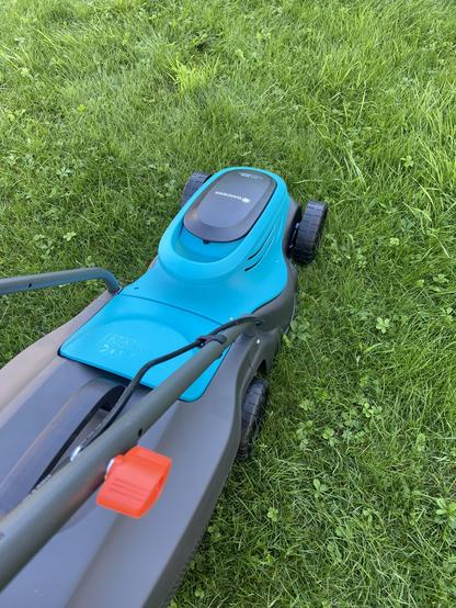 Ein Gardena EasyMax macht sich bereit den Rasen nach dem Urlaub zu schneiden. Unkraut ist auch mit am Start.