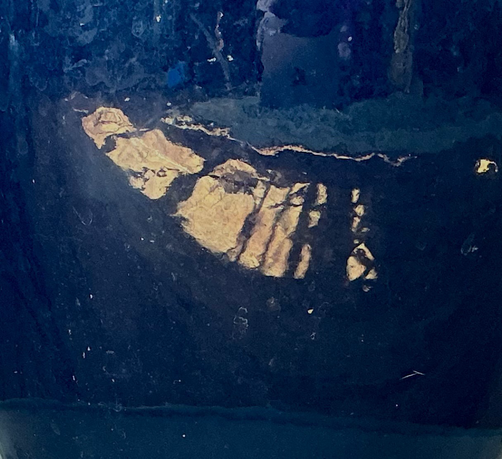A photo I just took of sunlight making interesting shadows on the floor. They are reflected on a dark blue plant pot… looks like a painting.