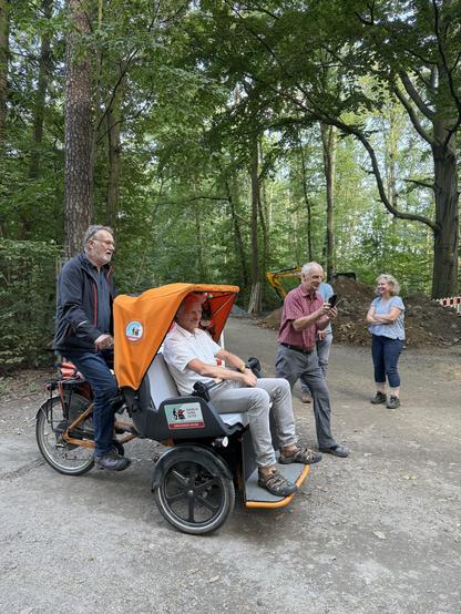 Einige Personen auf und neben der Rikscha