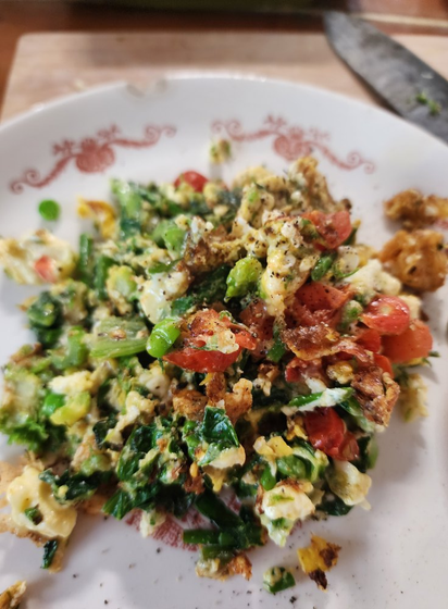 It's a scramble with lots of green, some peas showing, some tomato identifiable,  some pale bits but more veg than egg.  