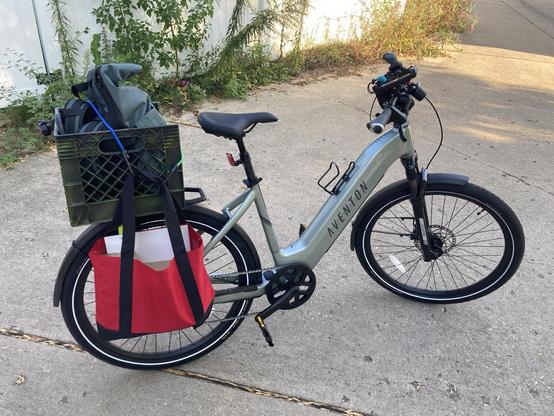 An ebike with a home made pannier and a milk crate on the rear rack. 