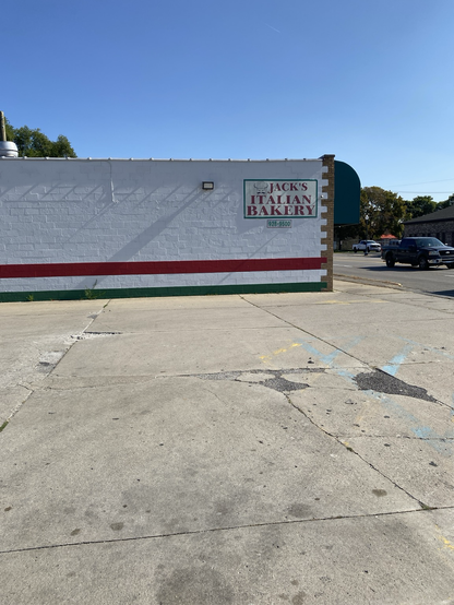 Jacks Italian Bakery. Photo of the side of a building. White wall, red stripe and green stripe. Best pepperoni rolls in the world.