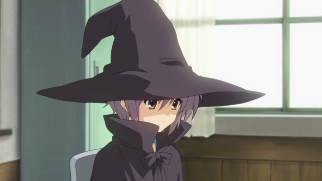A teenage girl (Yuki) with a neutral expression wearing a large black witch hat and black coat.