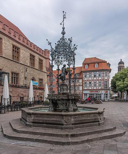 Der Gänseliesel-Brunnen in Göttingen mit der Bronzefigur eines Mädchens und Gänsen. Im Hintergrund sind das Alte Rathaus und Fachwerkhäuser am Marktplatz zu sehen. (Foto: A.Savin, Wikipedia)