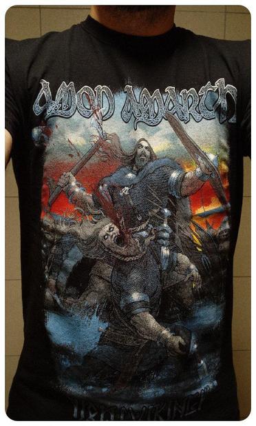 T-shirt du groupe Amon Amarth, pour la tournée de 2016, sobrement appelé Viking. 
Ce sont des suédois qui chantent sur des vikings donc le visuel... c'est une bataille de vikings, très original. 
On en voit un devant qui donne un coup de hache dans la face de ce qui doit être un ennemi. 
Donc visuellement, même si ça reste un dessin, ce n'est pas très joli. 
Ça reste un t-shirt de tournée, donc ça remonte le niveau mais c'est tout de même pas idéal pour prendre le métro. 
Acheté le 13/11/2016 pour le concert au Transbordeur.