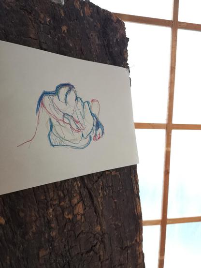 Un dessin de couleur bleu et rose est épinglé sur une planche en bois