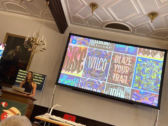Gemma on Stage, witch’s few of her colourful pieces on screen behind her