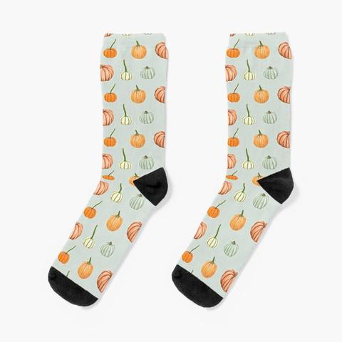 Chaussettes imprimées d'un motif composé de citrouilles et potirons peints à l'aquarelle sur un fond vert pastel.
