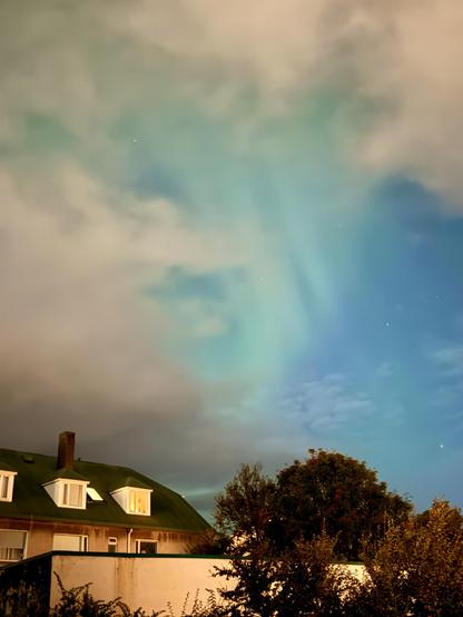 The view from my backyard showing a neighboring apartment block, trees, clouds, and the northern lights poking through