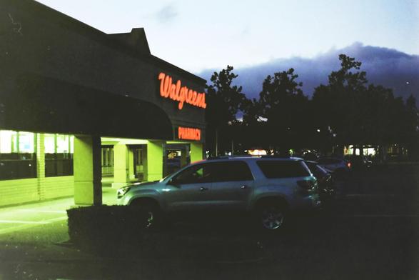 Dark shot of Walgreens with a car in the front and cloud on the back