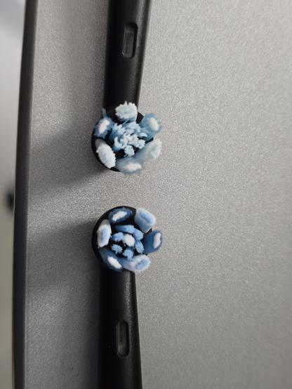 Two oral-b io toothbrush heads in black. The one coming down from the top was 14 days in use as is visibly damaged with frayed bristled and discolored indicators, the one coming up from the bottom of the photo is fresh out of the packaging for comparison.