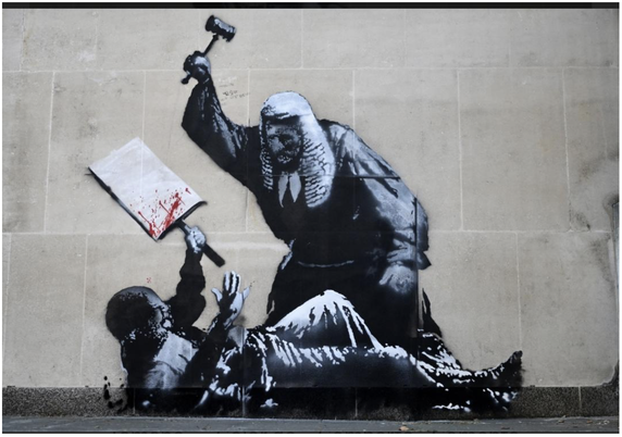 "Banksy Mural Depicting Attack by Judge
The work, painted onto the walls of one of Britain’s most important court buildings, showed a judge attacking a demonstrator with a gavel."