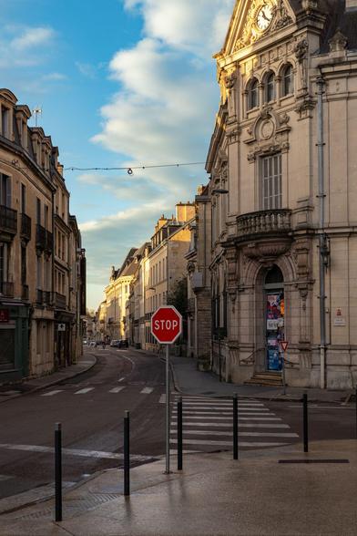 The golden hour casts a warm glow on the elegant streets of Dijon after a fresh rain. Even the stop sign looks beautiful in this light! 🛑☀️✨