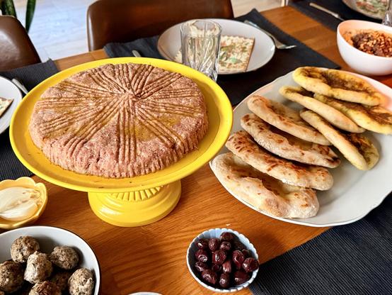 More plates, including a cake stand with kibbeh nayeh (raw lamb) and a plate with manaeesh (flat breads with zaatar and cheese)