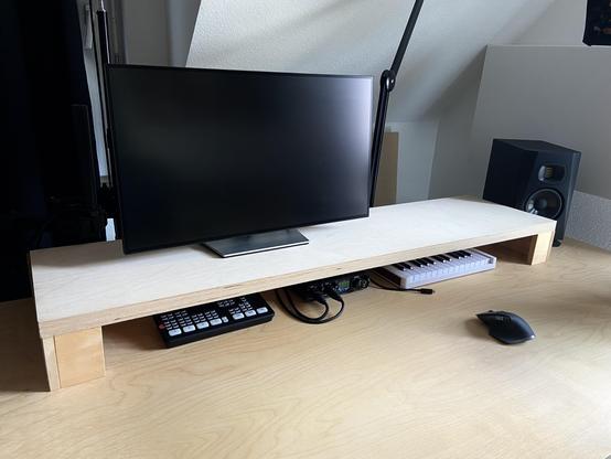A wooden desk with a board as a second “level” on top. An LCD monitor is placed on top of the board. Below it, an Atem Mini switcher, a MOTU M2 audio interface, and an Arturia MiniLab 3 keyboard are stowed away.