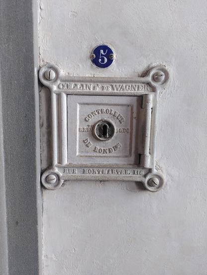In den Uffizien angebrachter Controleur de Rondes, produziert von einer Firma ansässig in der rue Montmartre 116, darüber ein rundes blaues Schild mit blauer Nummer 5.