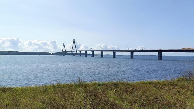 Long bridge over clam water with a blue sky behind it