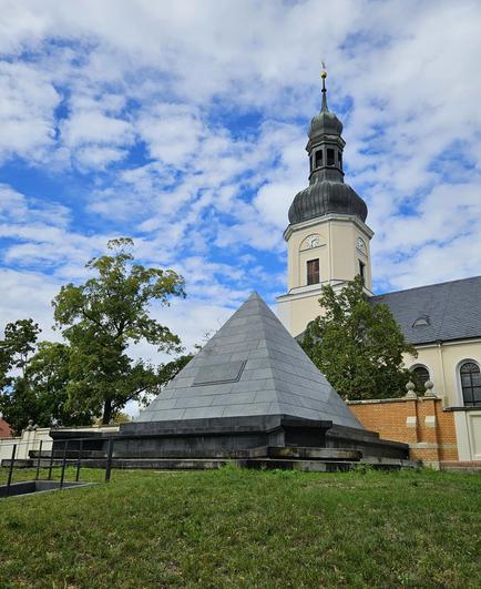 Außenansicht der restaurierten Begräbnispyramide der Familie von Eberstein in Leipzig-Schönefeld mit glattem schwarzen Stein.