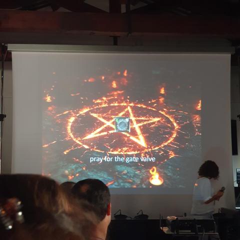 Slide showing a burning pentagram, the picture of a small device and the words "pray for the gate valve" 