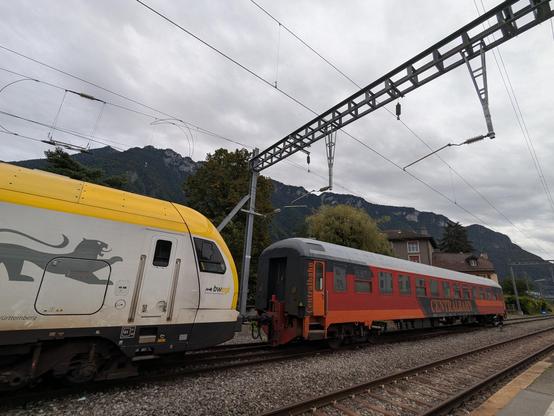 Un ancien véhicule de type UIC aux couleurs rouge foncé et orange de la Centralbahn est accroché à un FLIRT Stadler récemment équipé en ETCS par Alstom à Villeneuve VD.