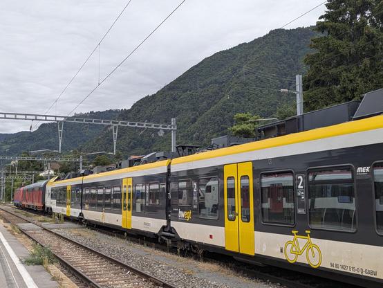 Un ancien véhicule de type UIC aux couleurs rouge foncé et orange de la Centralbahn est accroché à un FLIRT Stadler récemment équipé en ETCS par Alstom à Villeneuve VD.