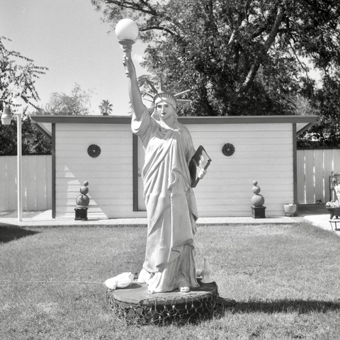A black and white film photo. A scaled-down replica of the Statue of Liberty sits in the middle of someone’s backyard in Crystal City, Texas. Saturday, August 30, 2025.