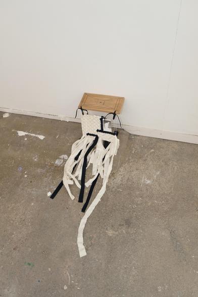 un autre bout de bois sur lequel des formes géométriques sont dessinées, vissé au mur près du sol cette fois, même système (grillage à poule et tissage) cette fois avec du tissu blanc et bleu très sombre, les lianes traînent au sol 